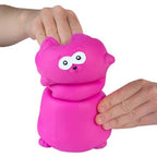 Pink cat shaped stress reliever toy being squeezed by a hand on a white background