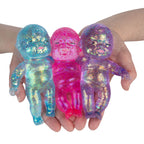Three colorful, iridescent baby dolls held in hands against a white background