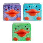 Three square lip-shaped duck cubes in purple, blue, and green with orange lips on a white background.