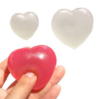 A translucent heart-shaped stress toy shown being squeezed by a hand, with two additional unpressed translucent heart toys floating above on a white background.