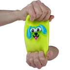 Hand holding a green dog-shaped smusher stress reliever toy against a white background