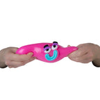Pink squishy smusher toy with googly eyes and a smile held between two hands on a white background
