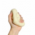 Hand squeezing cheese block squishy toy flat showing extreme softness
