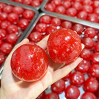 Hand holding two glossy red watermelon ice ball squishies